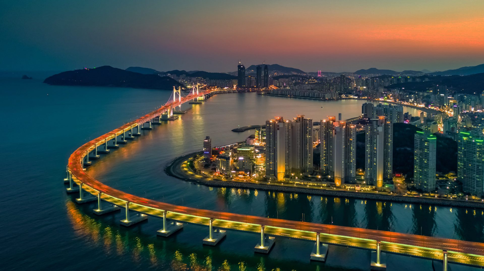 View across the water of the Busan skyline illuminated in different colours at night
