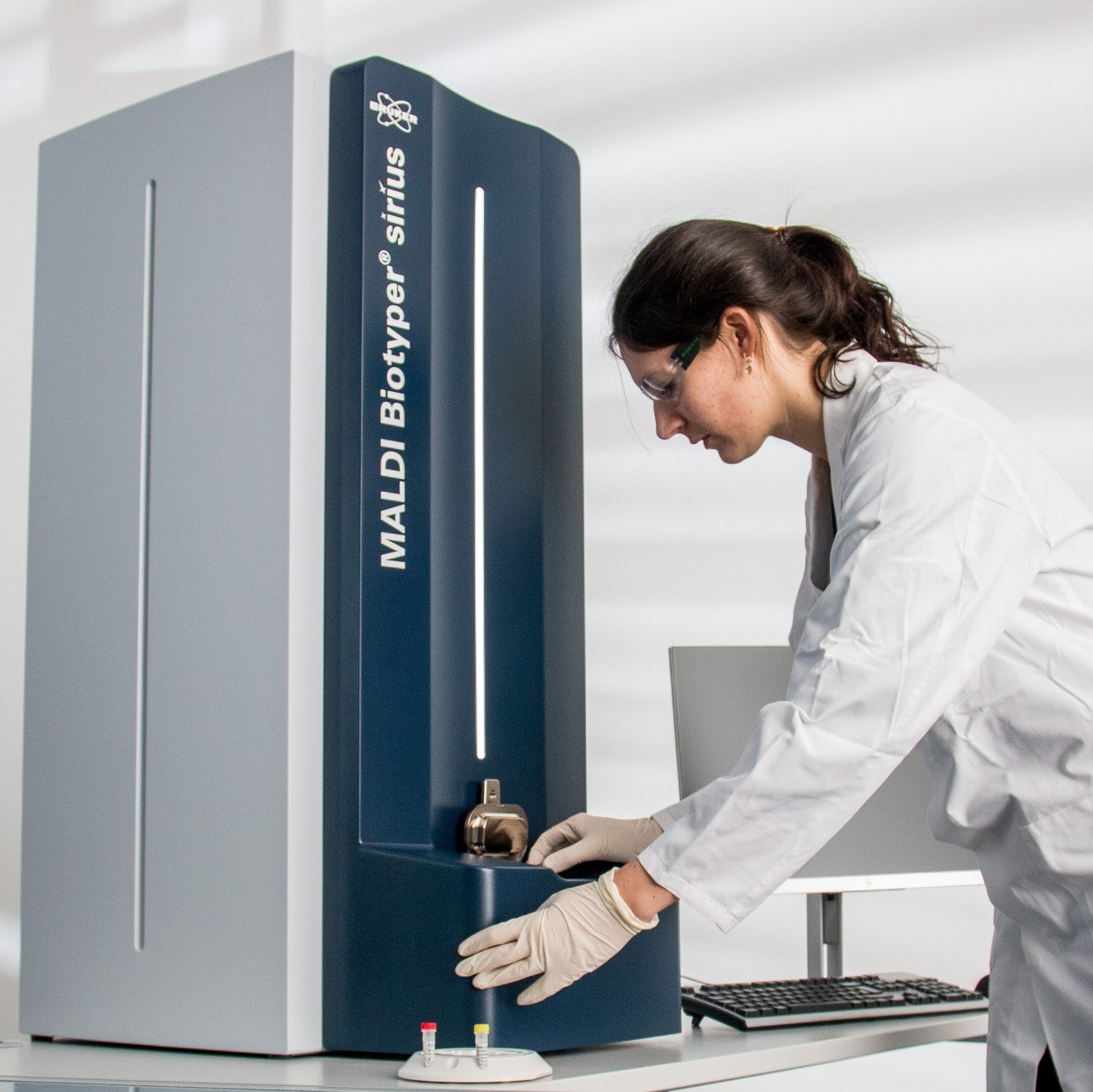 A woman in a lab coat loading a sample plate into a MALDI Biotyper sirius